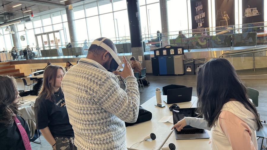 A person is wearing a virtual reality helmet as other people watch.